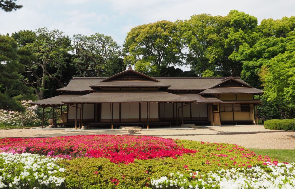 皇居外苑・東御苑にある施設の写真。中央に施設はあり、古い日本家屋のような見た目。手前には花壇がある。施設の奥には木々がある。