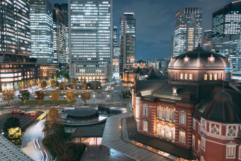 丸の内の景色を捉えた写真。左側に右側を向く東京タワー。その目の前には広場が広がっていてその周辺を高層ビルが取り囲む。